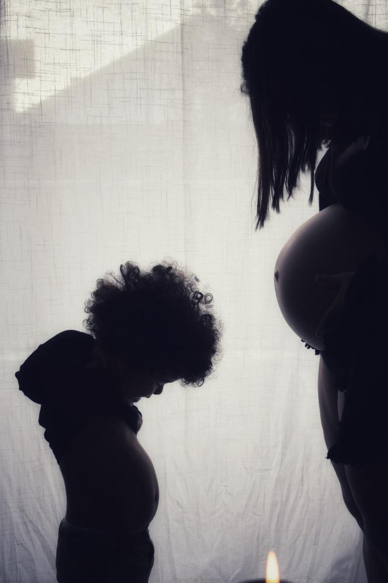 Silhouette d'un enfant qui imite le ventre rond de sa maman enceinte