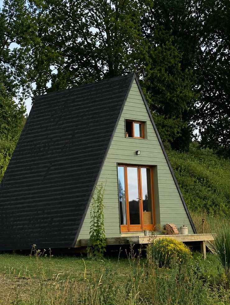 Le Nidou, petite cabane en A vert sauge au milieu des arbres