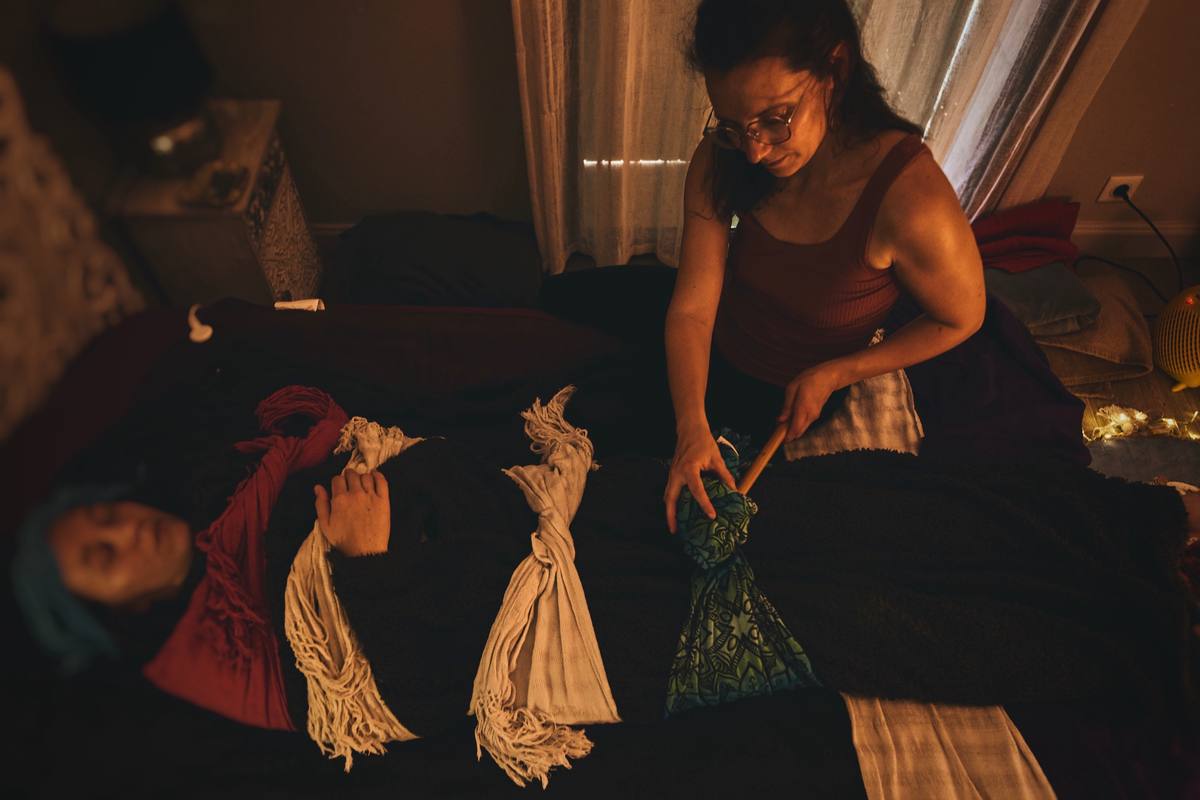 Une maman allongée, le corps emmailloté dans les écharpes rebozo, pendant le serrage