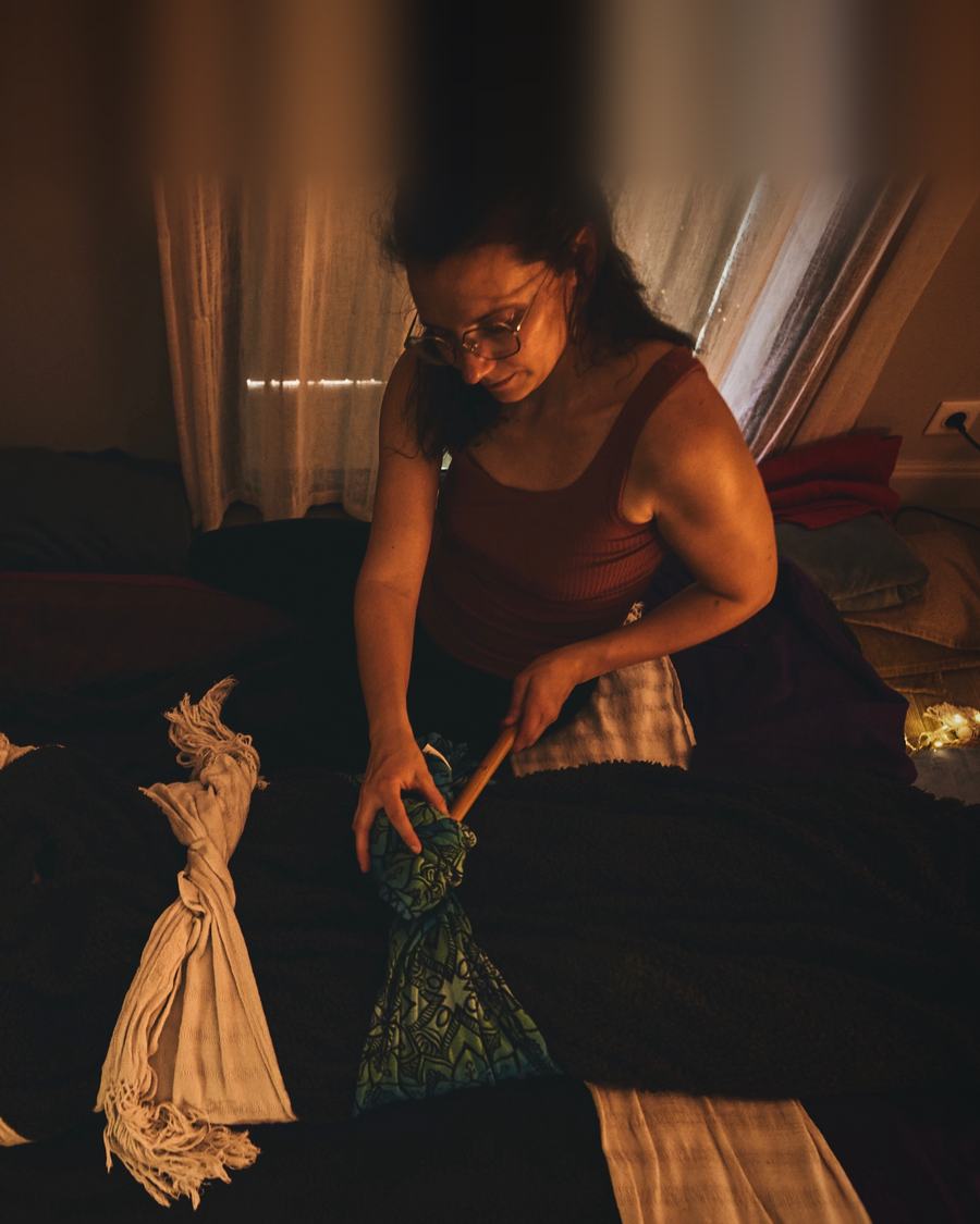 Andréa pendant un serrage au rebozo, penchée vers une maman allongée